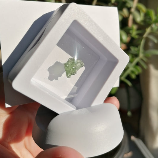 Green Moldavite in white stand