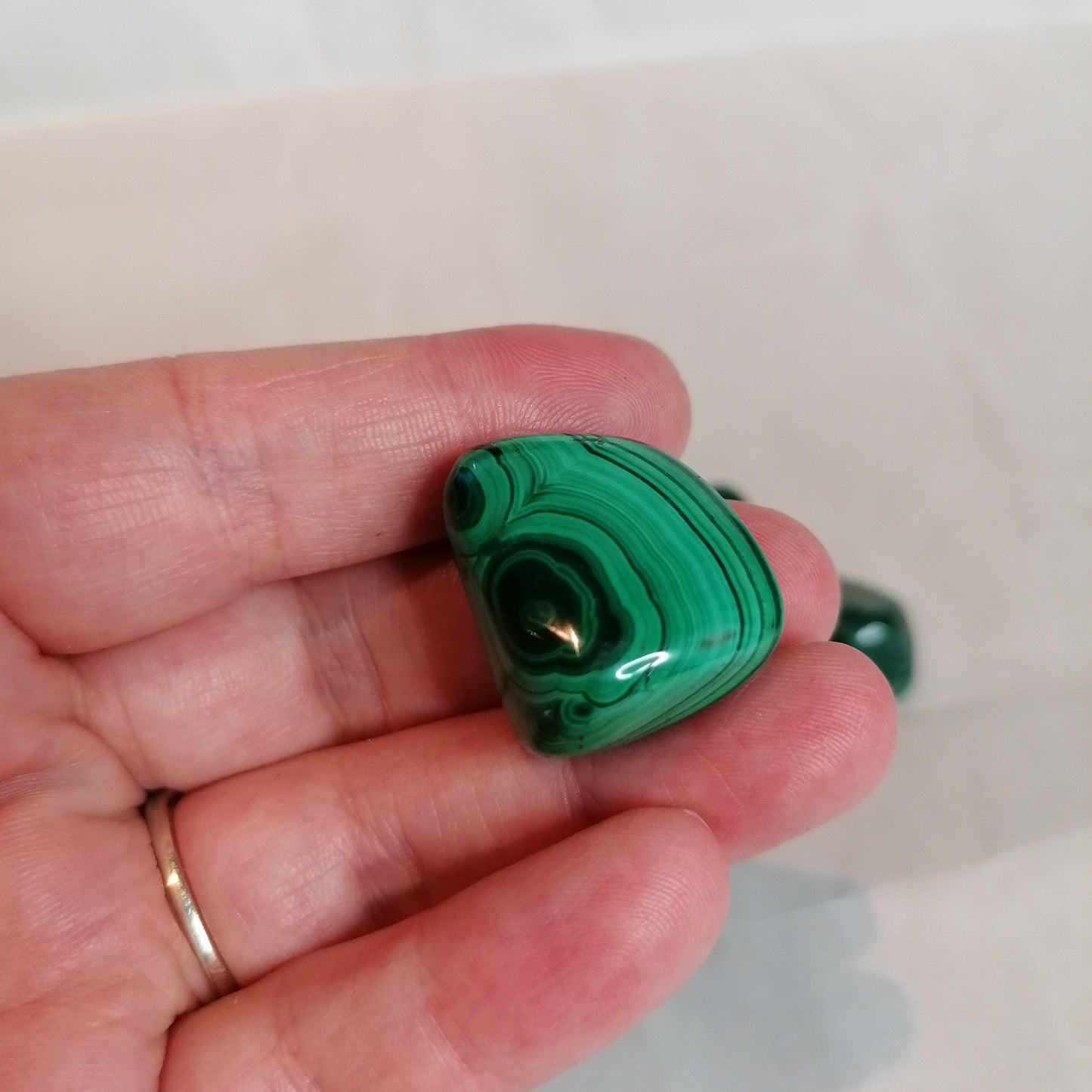 close up of the green spiral pattern on a singular malachite crystal tumblestone