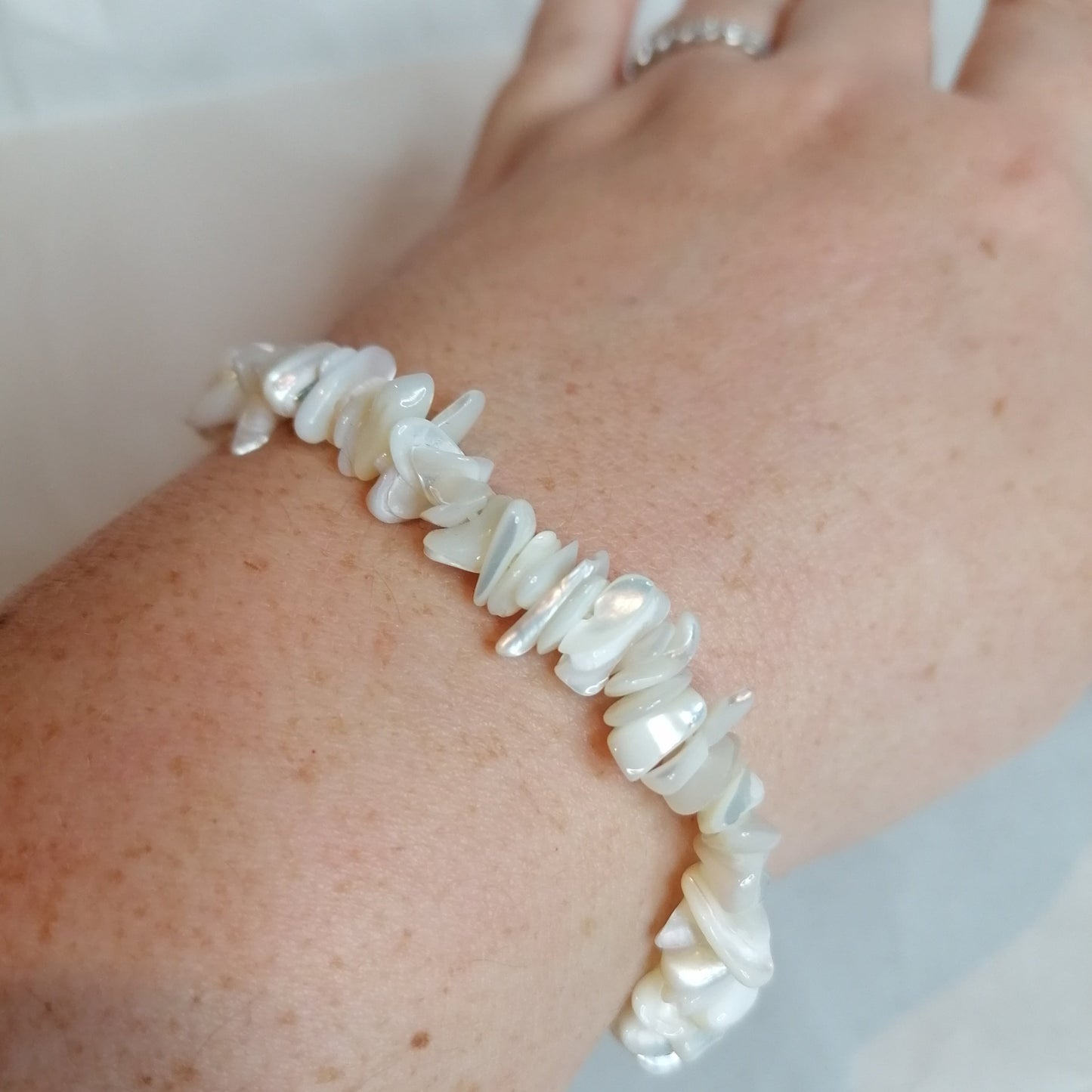 A white mother of pearl crystal chip bracelet on a wrist