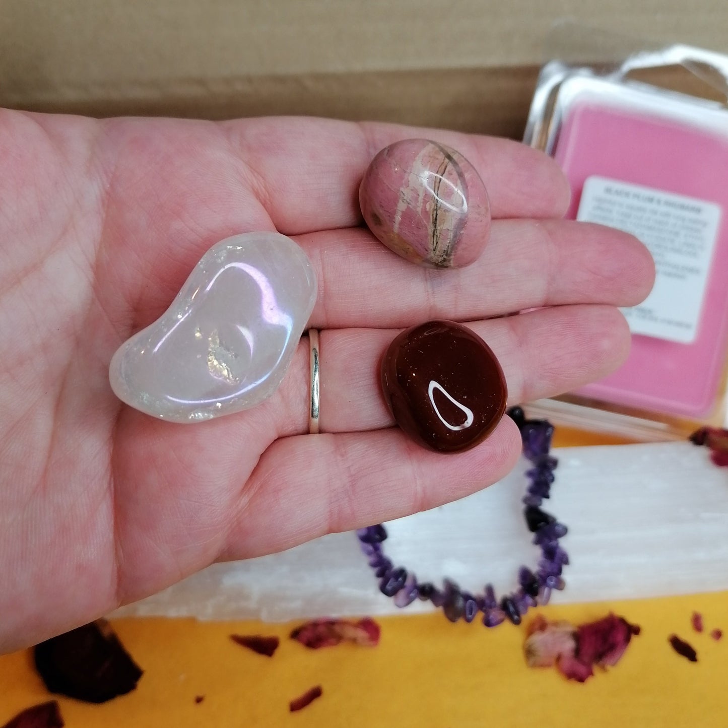 close up look at the tree tumbles, pink aura rose quartz, pink and black rhodonite and a red carnelian