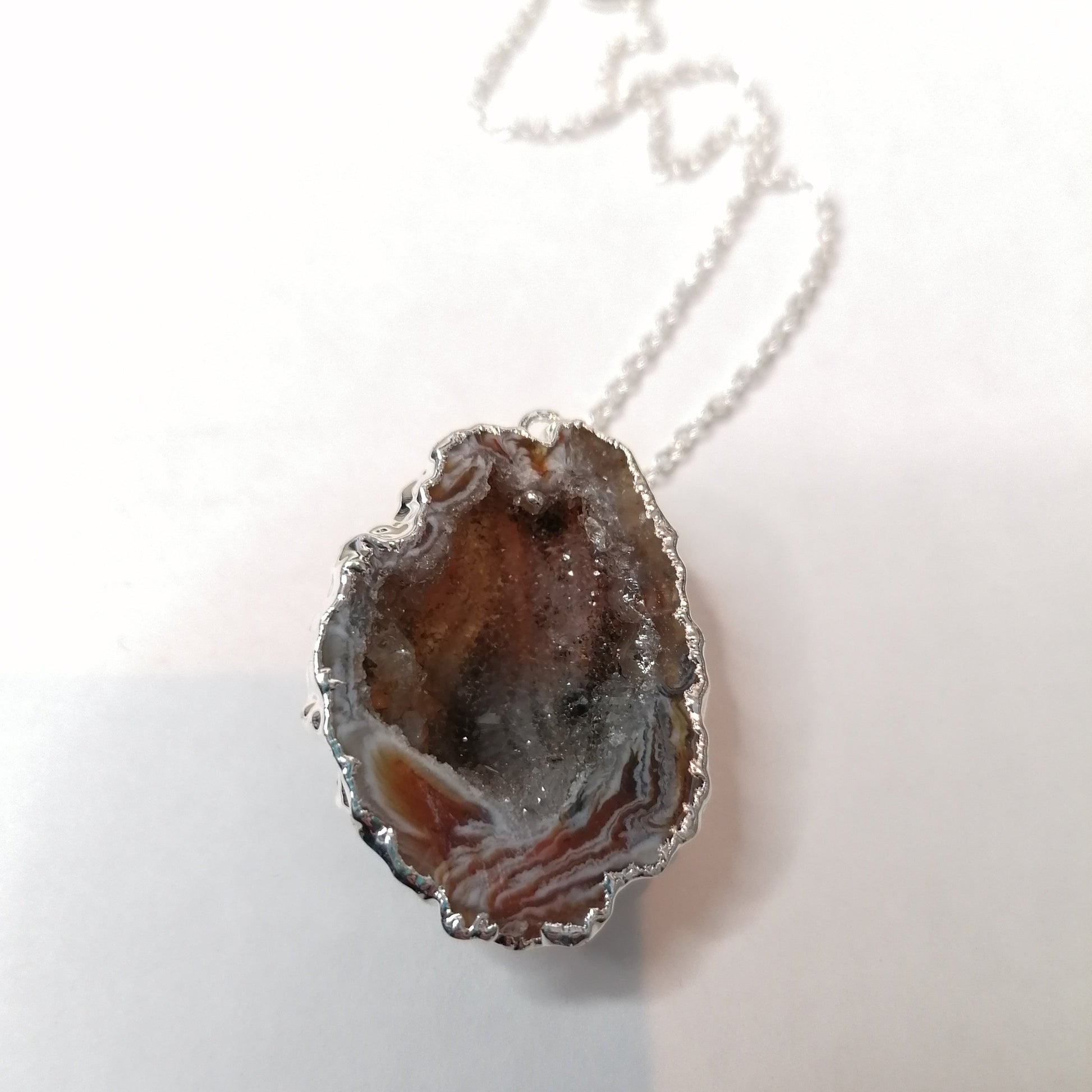 half geode wrapped in silver on a silver necklace chain