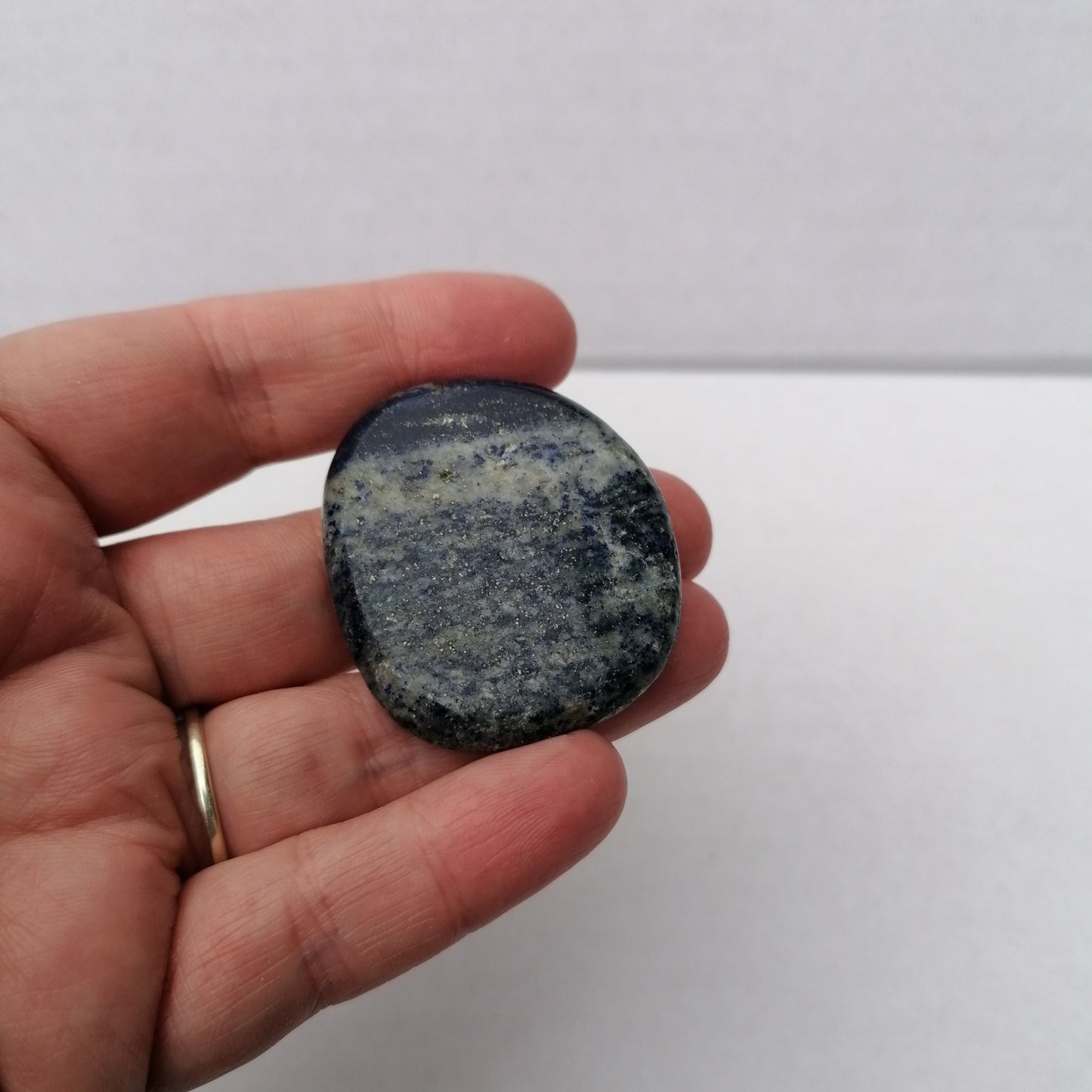 blue gray and gold lapis lazuli smoothstone in a hand