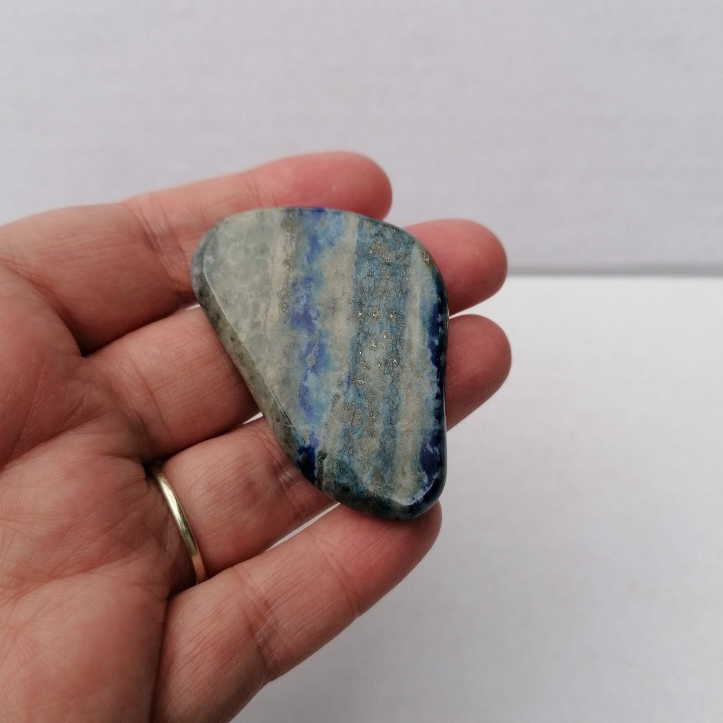 close up of a blue grey and gold banded lapis lazuli smoothstone