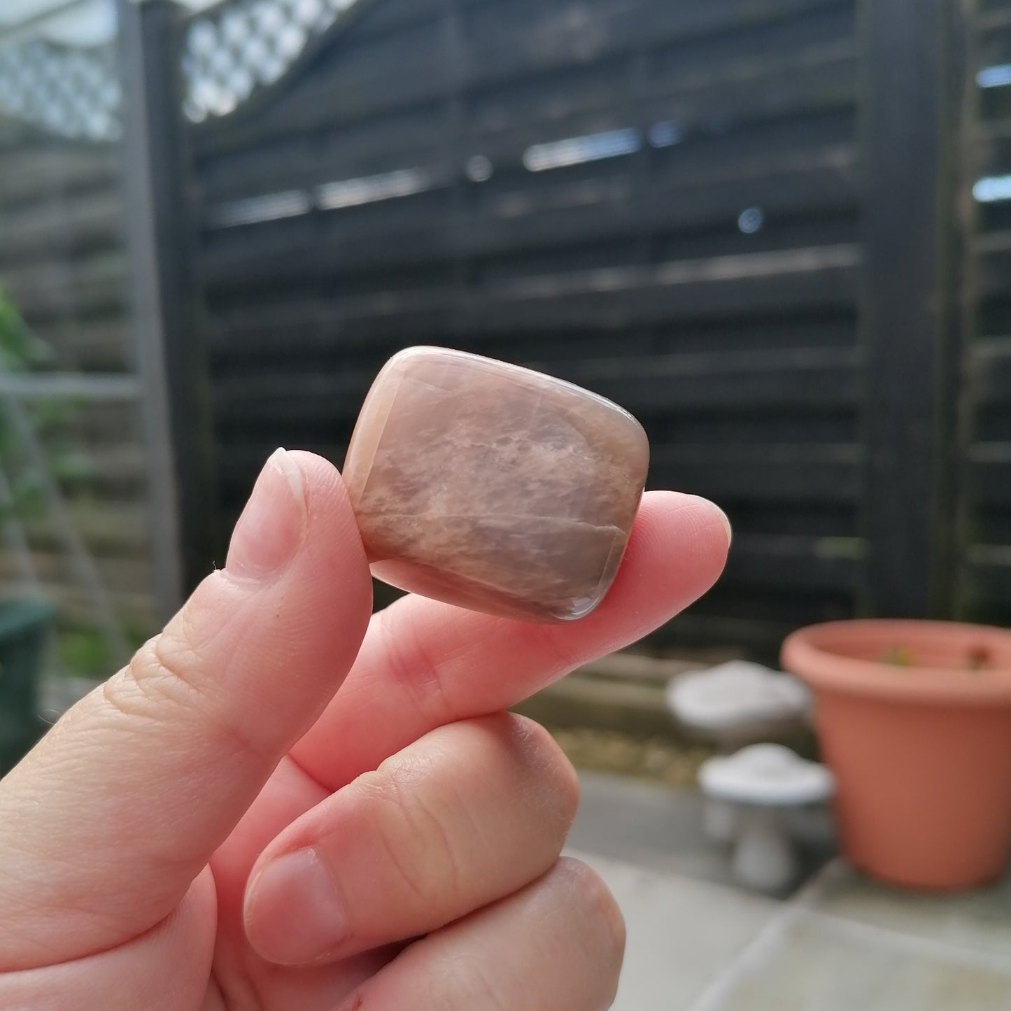 black moonstone tumble held up close in the light