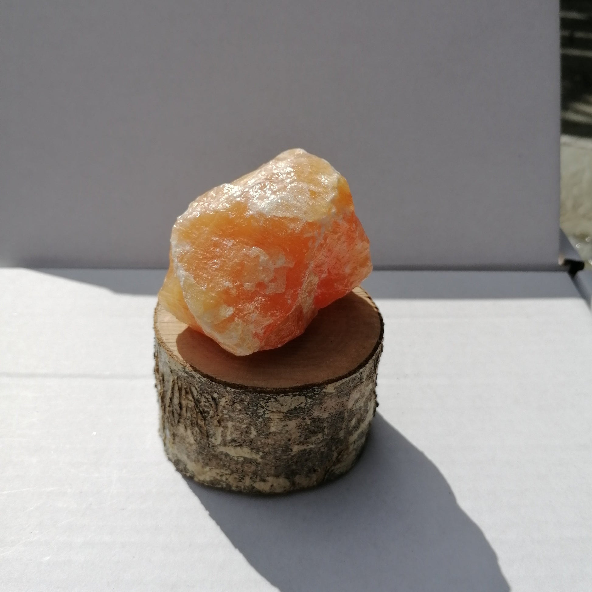 large orange calcite raw chunk on wooden display