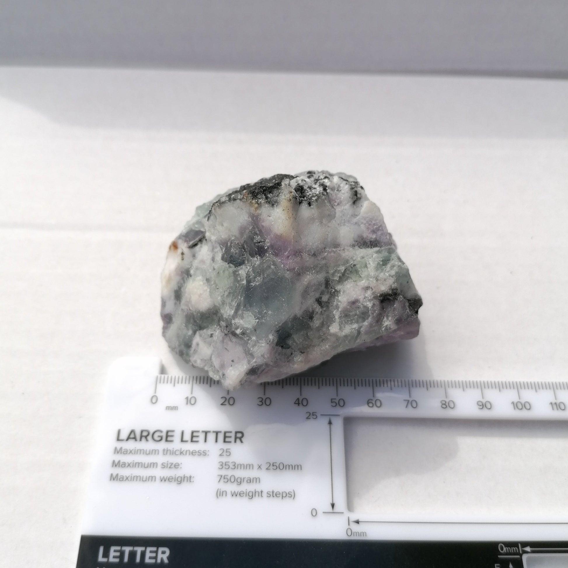 rough raw fluorite chunk measuring 70mm next to ruler