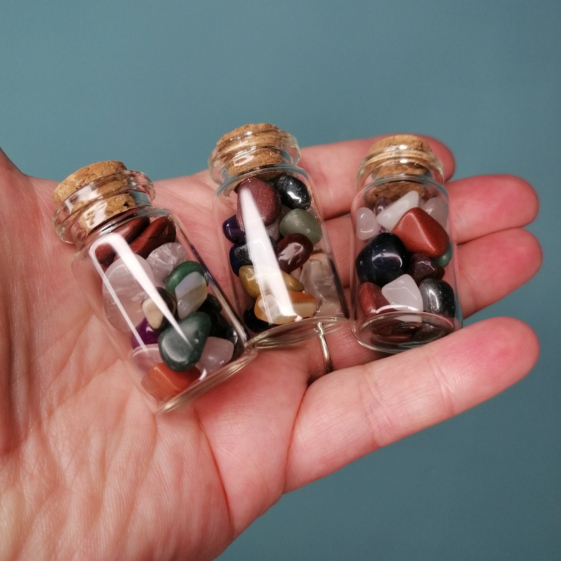 three small glass bottled filled with mixed colour crystal chips