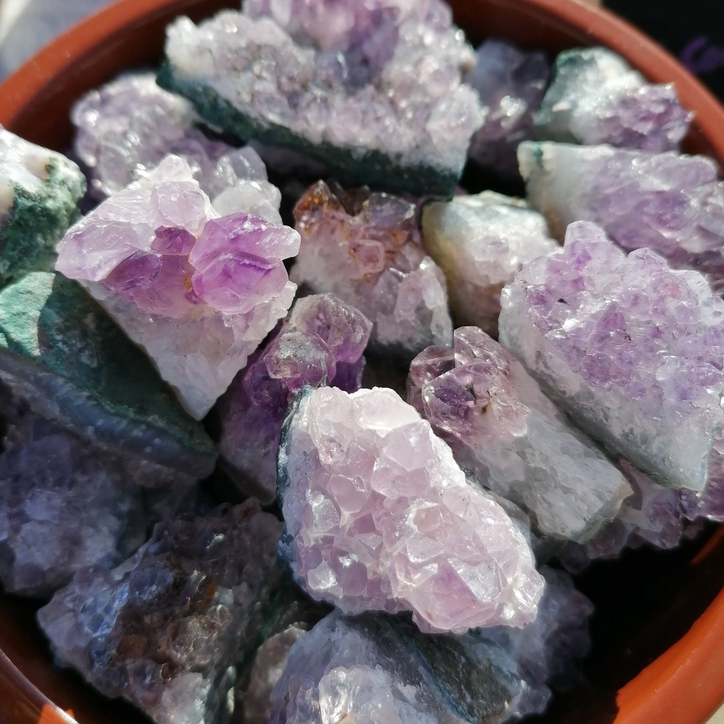 a brown dish full of purple amethyst cluster crystals