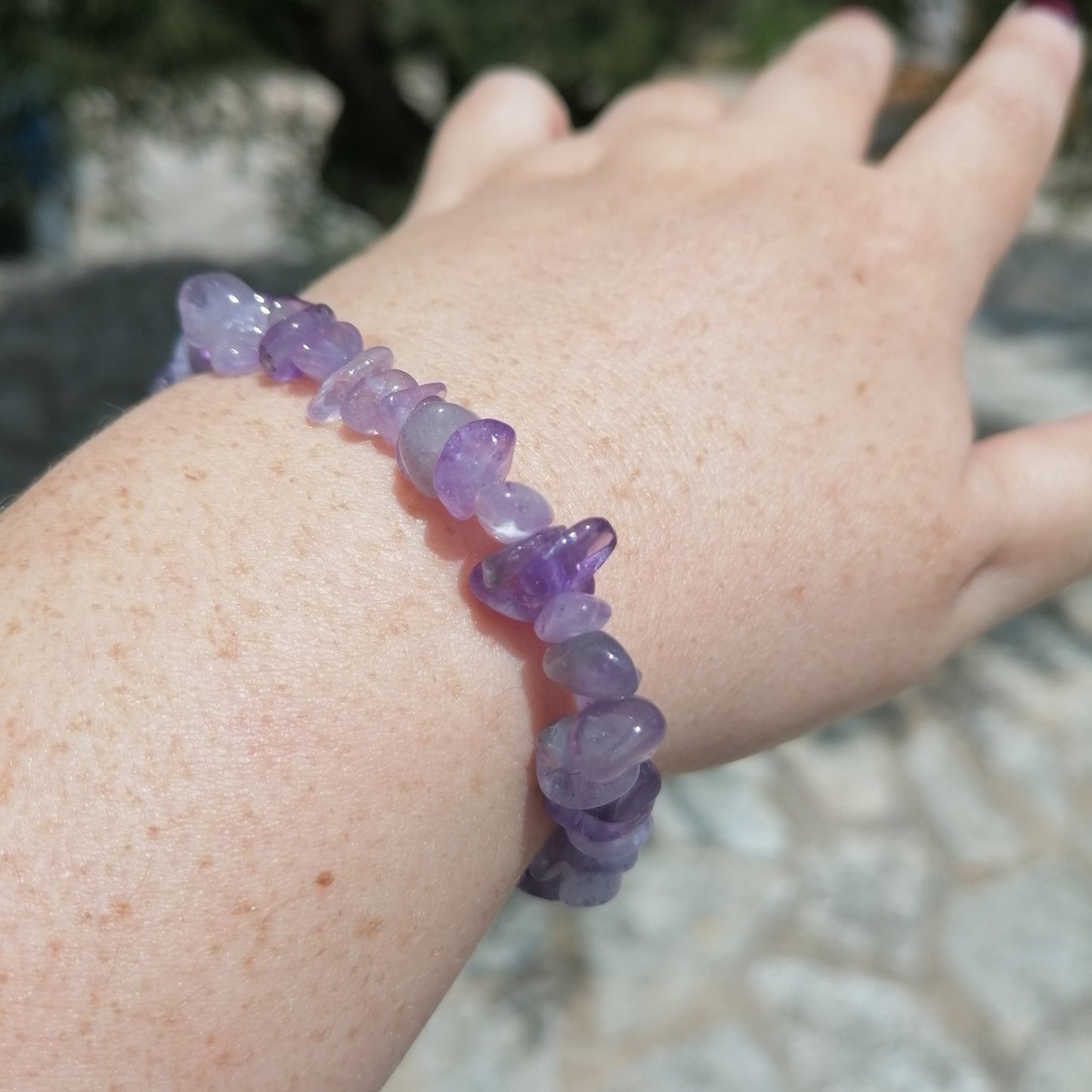 a dark purple amethyst crystal chip bracelet on a women's wrist