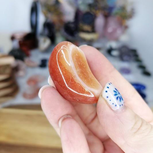 Hand holding a polished carnelian stone with white banding
