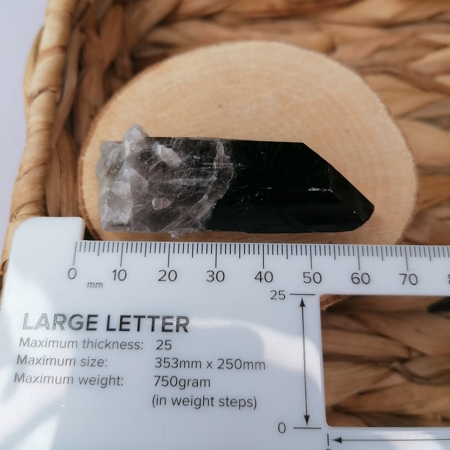 long dark brown smokey quartz point next to ruler to show a size of 60mm