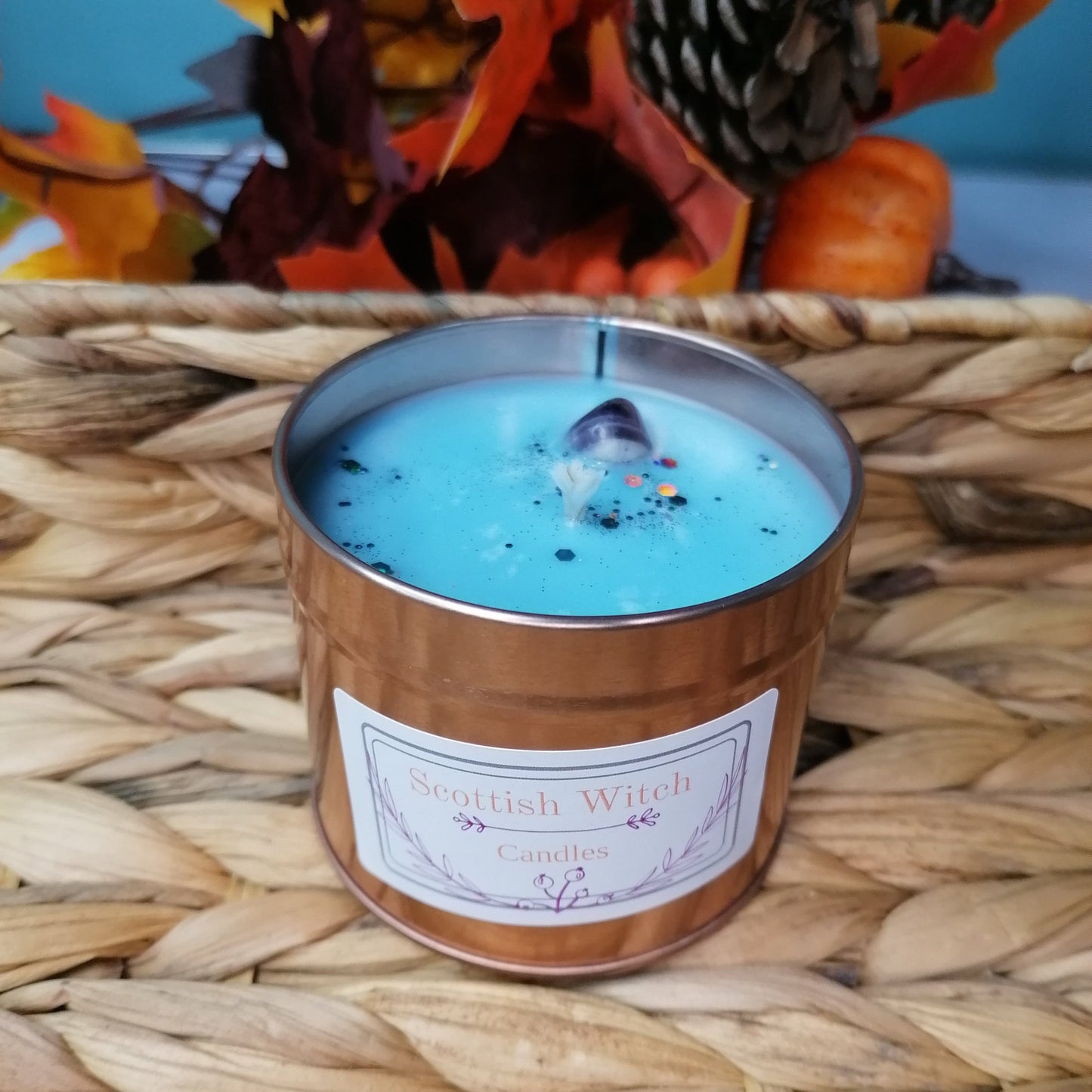 A White Winter scented christmas candle with blue wax in a rose gold tin decorated with amethyst crystal and glitter