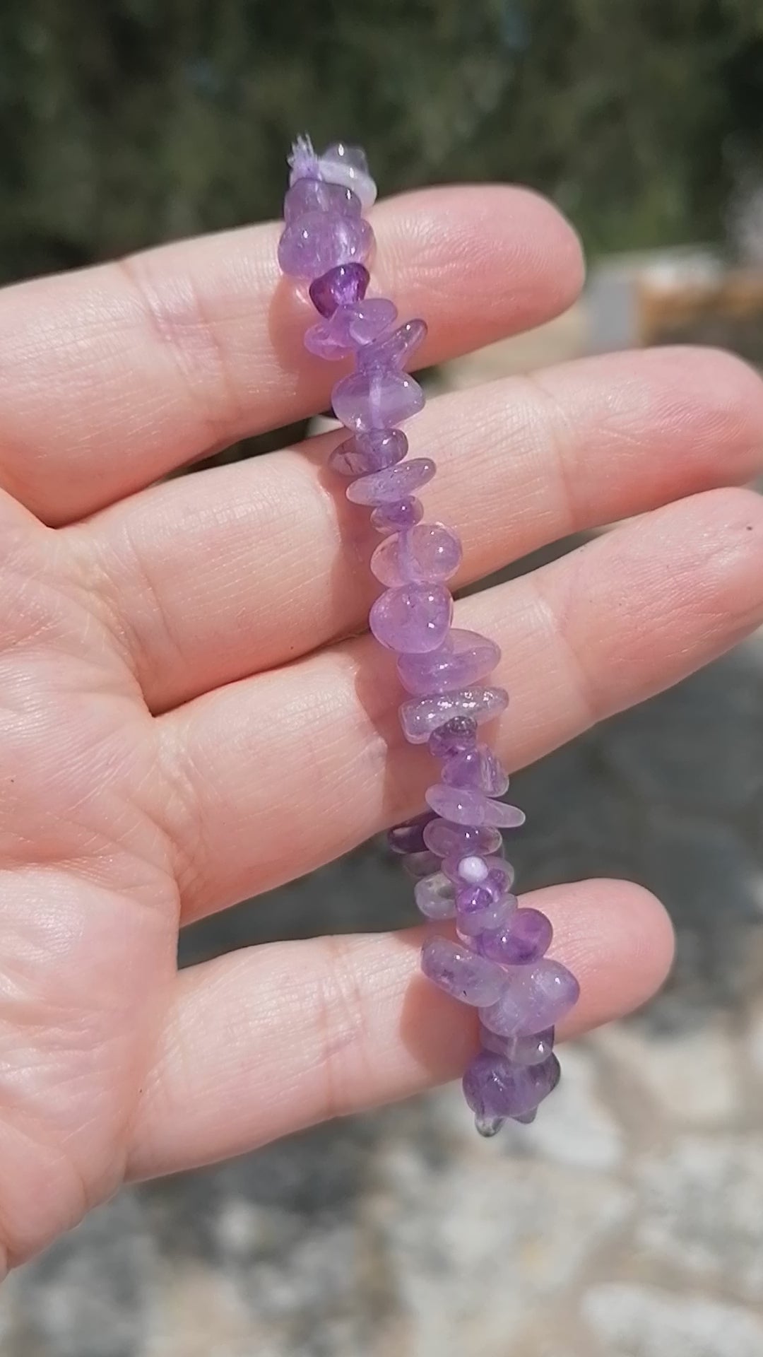 a dark purple amethyst crystal chip bracelet being rotated so you can see all the crystals