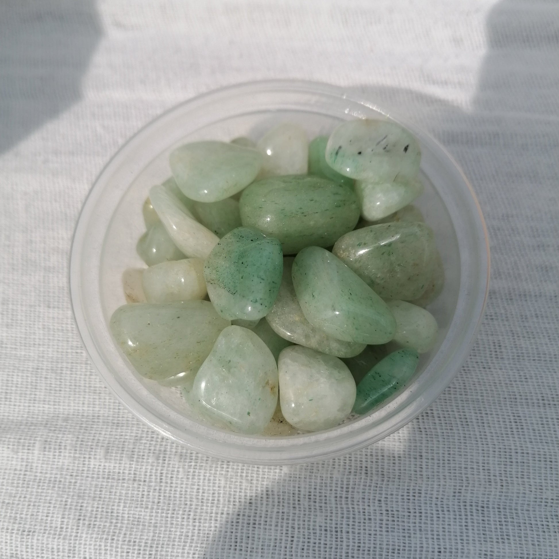 a small dish of light green aventurine small tumblestones