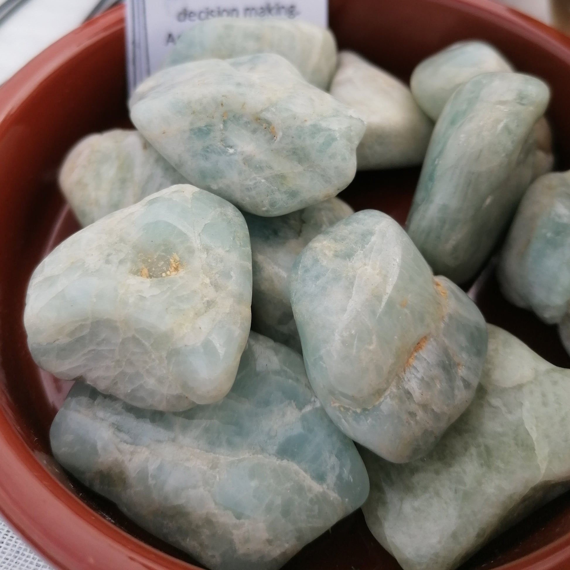 A brown dish of light green aquamarine crystal tumblestones