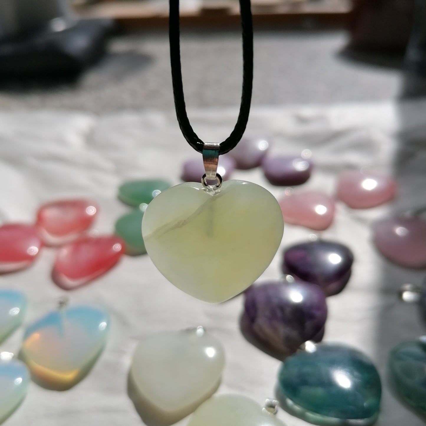 a light green new jade heart shaped crystal necklace on a black chord chain