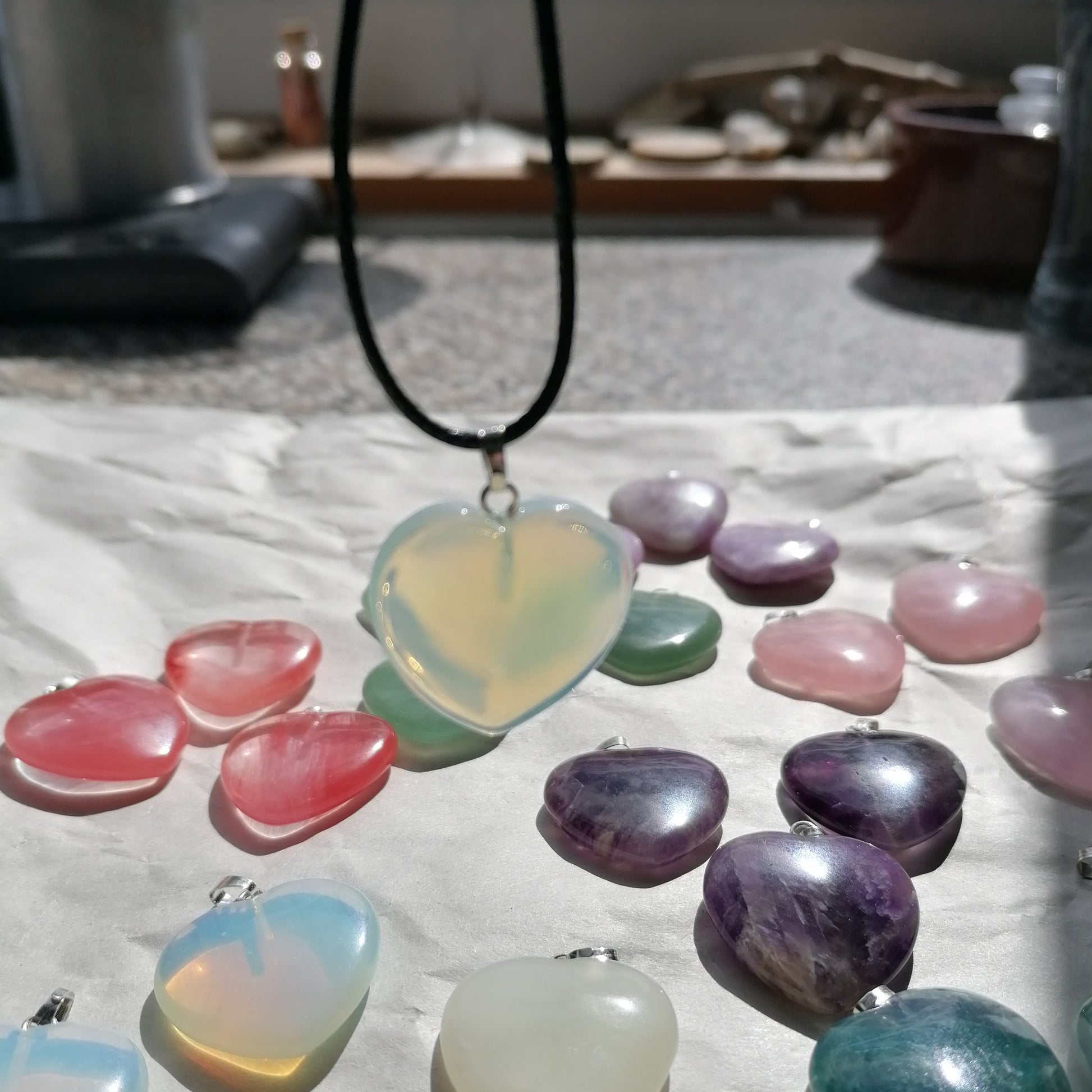 a white opalescent Opalite heart shaped crystal necklace on a black chord chain