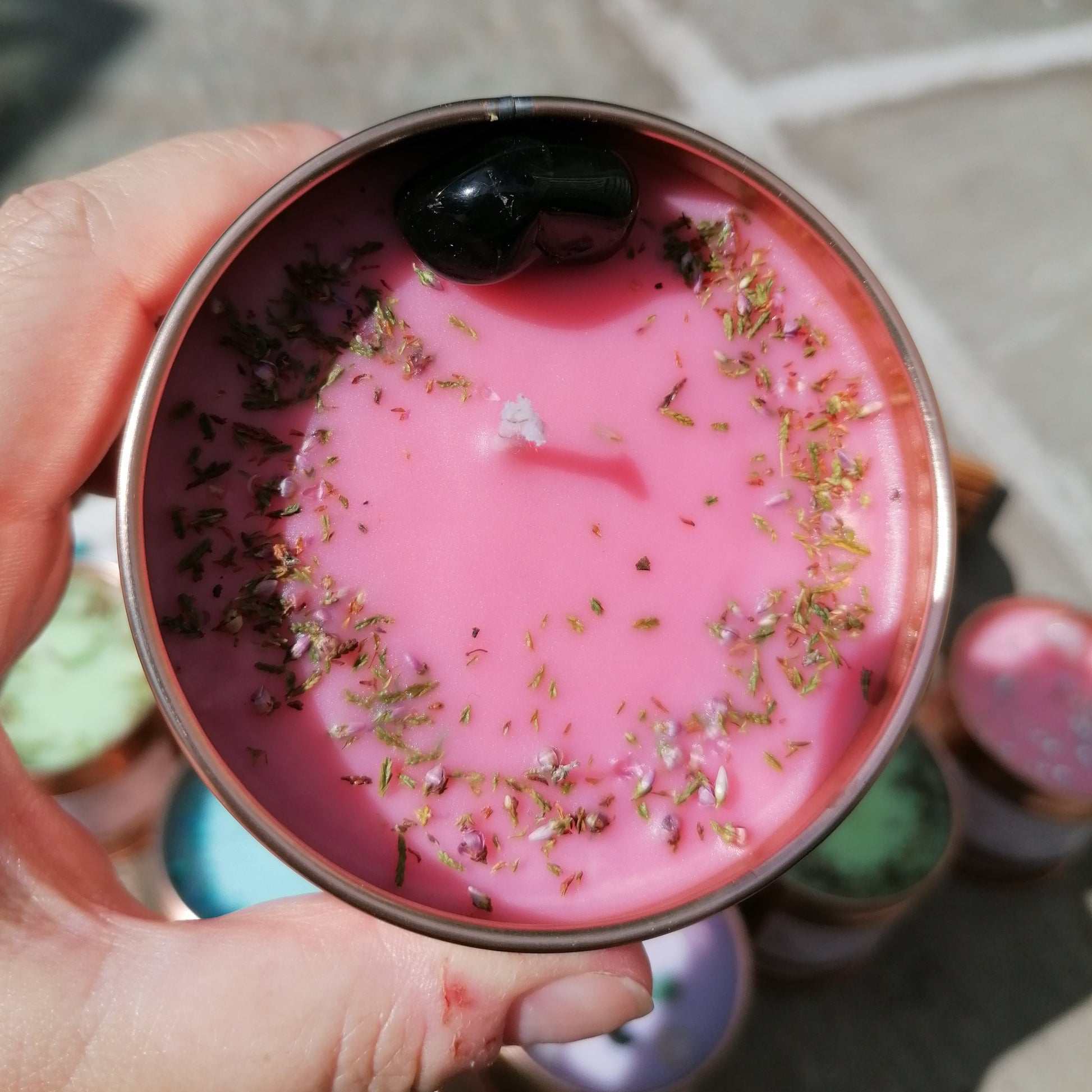 a pink candle in a rose gold tin decorated with a black onyx crystal and scottish heather