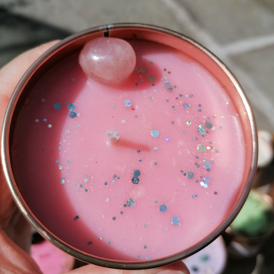 a pink candle in a rose gold tin decorated with silver glitter and a rose quartz crystal