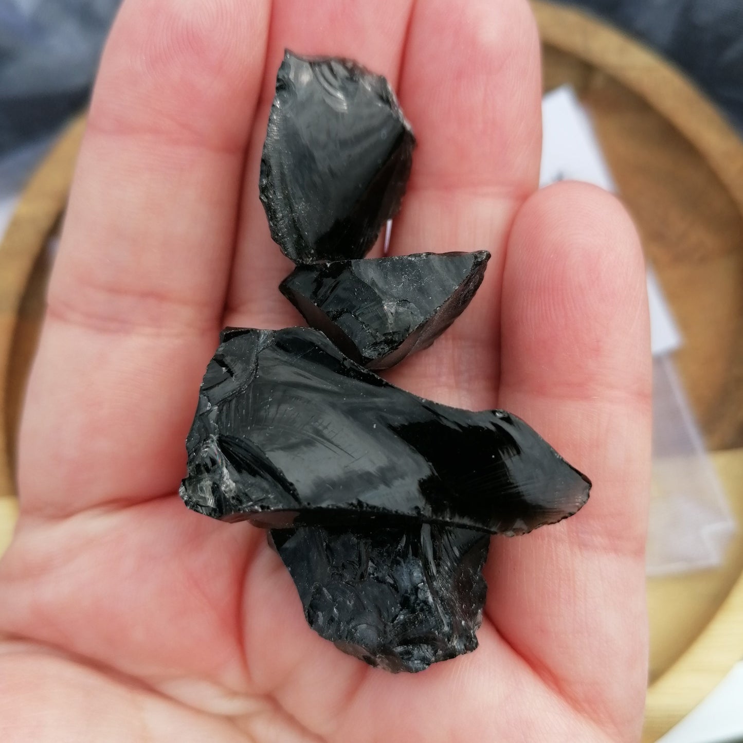 a handful of raw black obsidian chunks on a hand