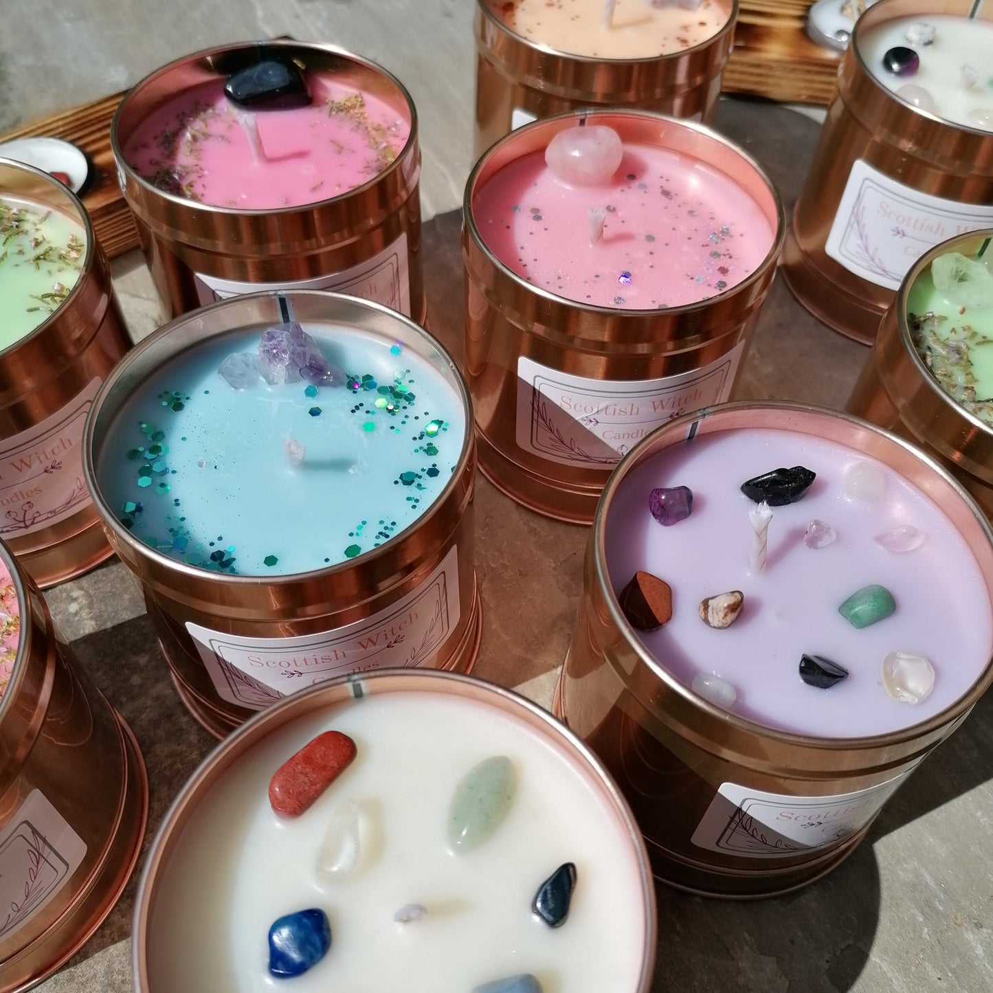 selection of colourful candles all in rose gold tins and all decorated with colourful crystals