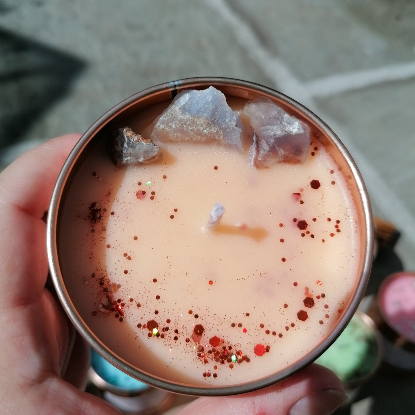 orange candle in a rose gold tin decorated with glitter and blue lace agate crystals