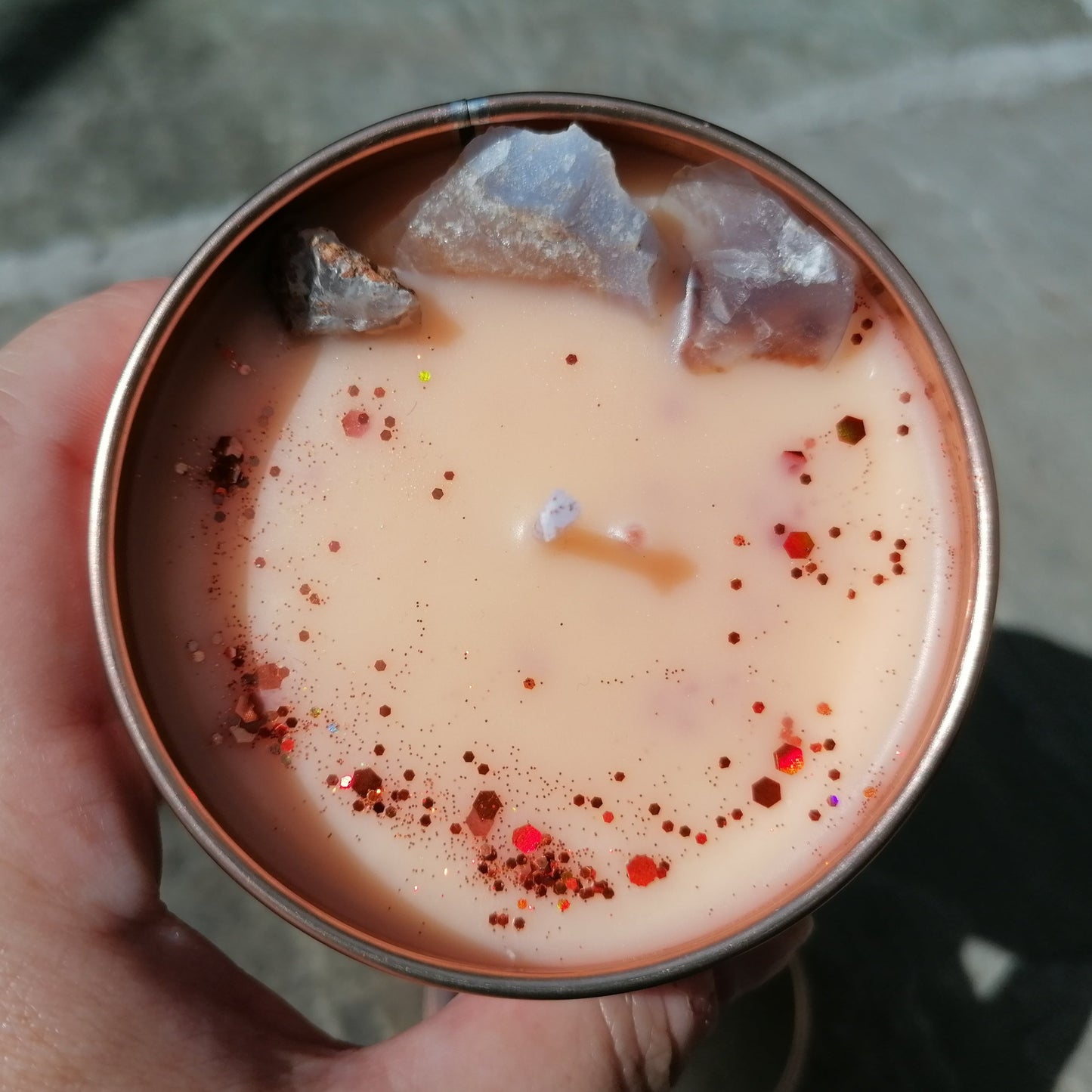 orange candle in a rose gold tin decorated with glitter and blue lace agate crystals