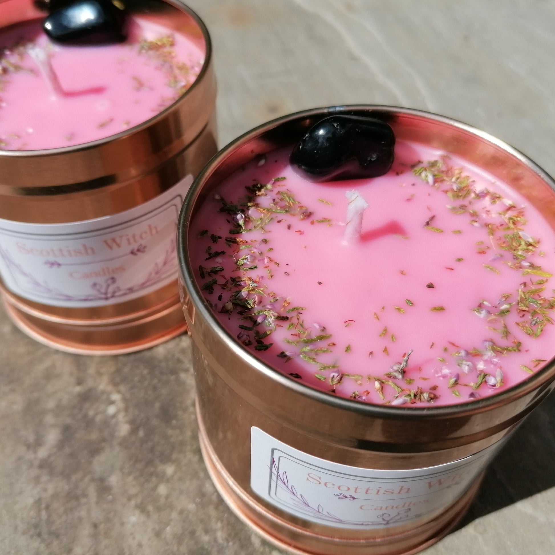 two pink candles in rose gold tins decorated with black onyx crystal and scottish heather