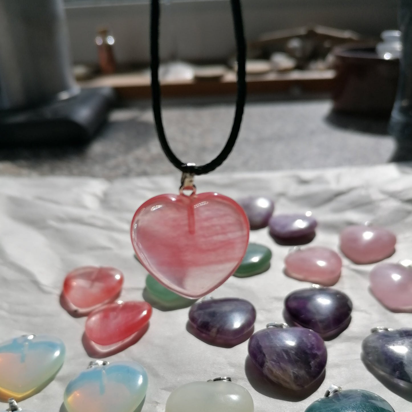 a red cherry quartz heart shaped crystal necklace on a black chord chain