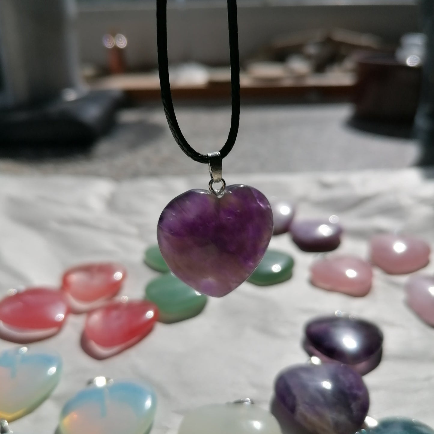 a purple amethyst heart shaped crystal necklace on a black chord chain