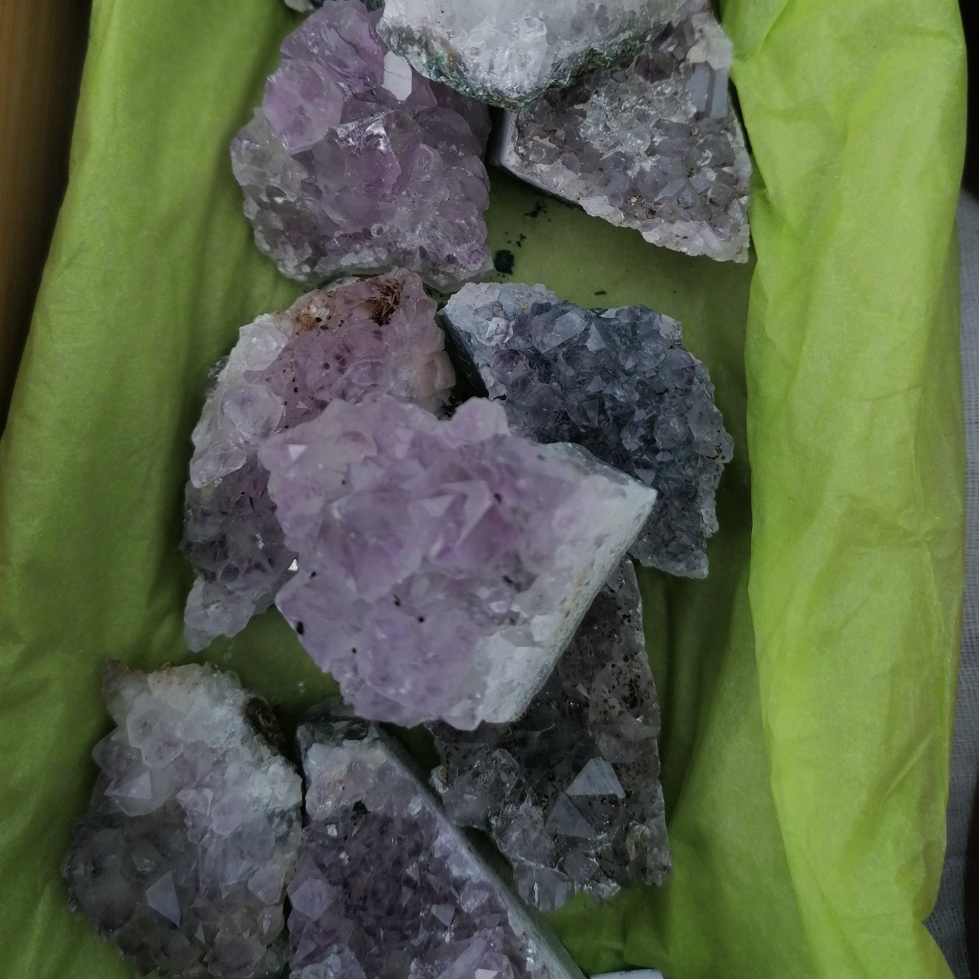 Small purple amethyst cluster crystals on a tray